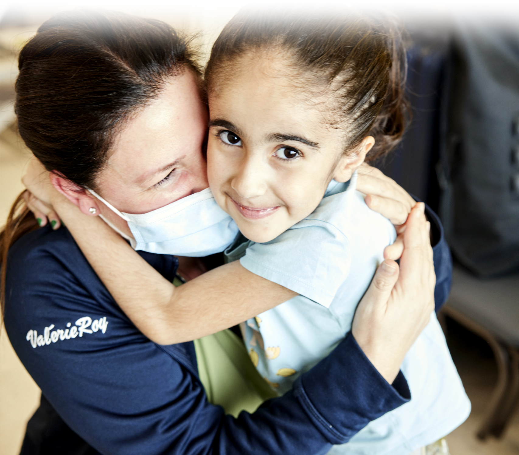 Seven-year-old Eva with her arms affectionately wrapped around the neck of her nurse at Sainte-Justine.