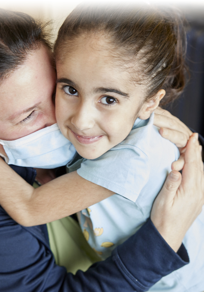 Seven-year-old Eva with her arms affectionately wrapped around the neck of her nurse at Sainte-Justine.