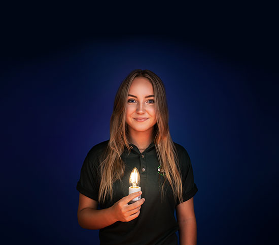 Sur fond bleu foncé, une adolescente à la peau pâle tient une ampoule qui illumine son visage.