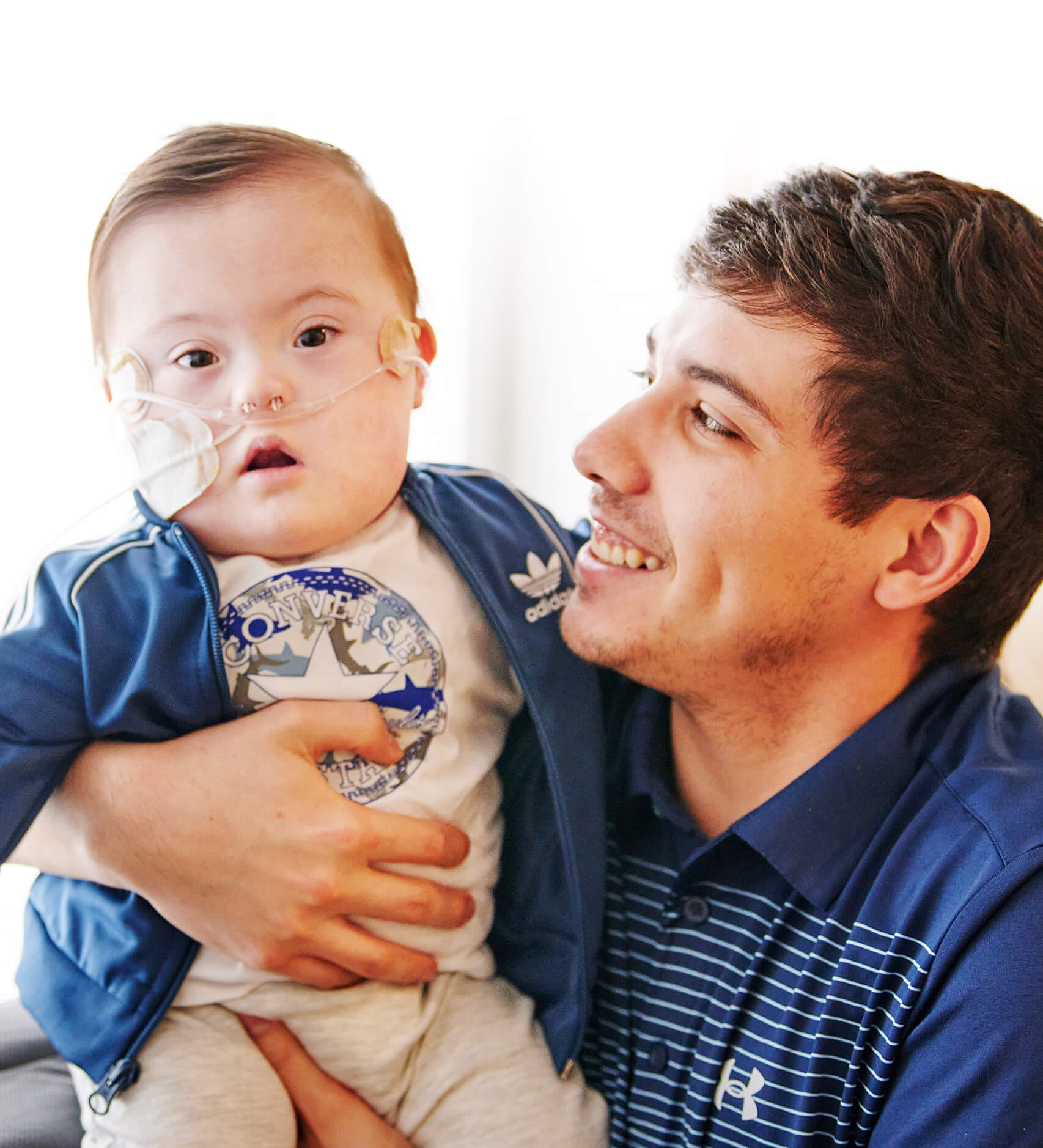 Jasper, un patient bébé, est dans les bras de son papa qui le regarde tendrement.