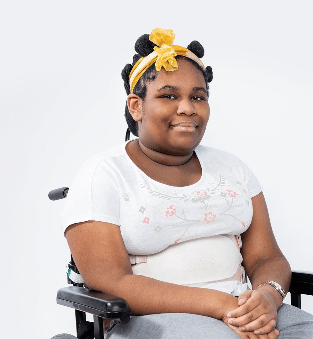 Kayla, une jeune patiente du Centre de réadaptation Marie Enfant du CHU Sainte-Justine, assise dans son fauteuil roulant..